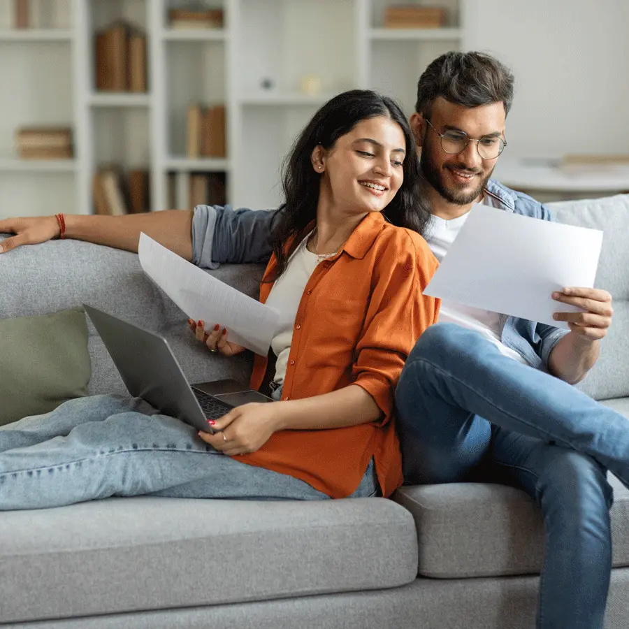 Ein Paar profitiert vom günstigen Stromtarif und schaut glücklich in die Rechnung.